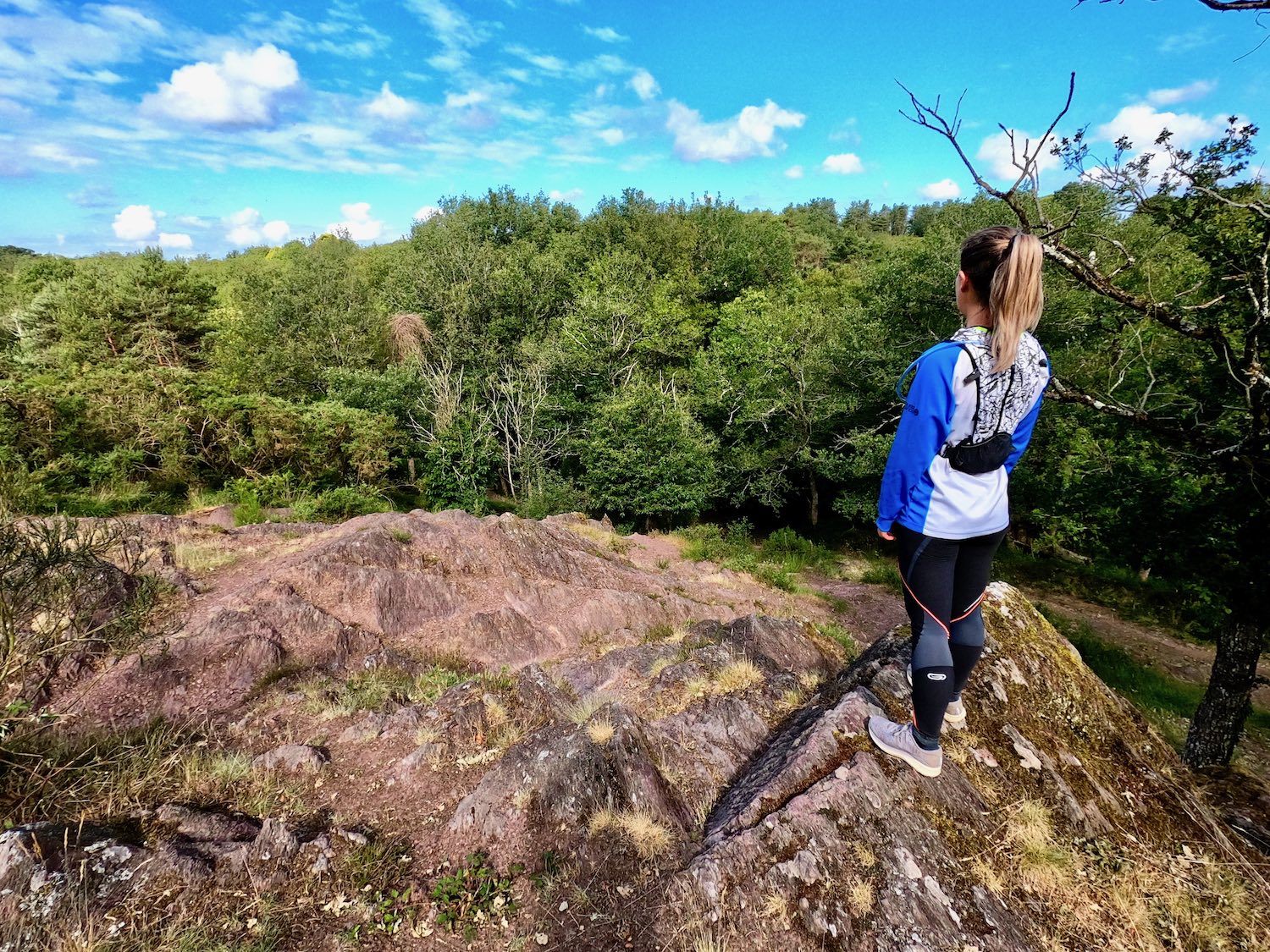 Femme souriante en tenue colorée sur un sentier en forêt à l'aube